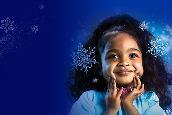 A child smiling as snowflakes fall around her.
