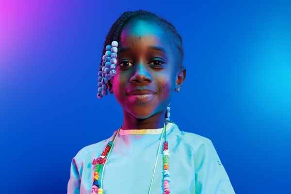 A child wearing colourful bravery beads around their neck.