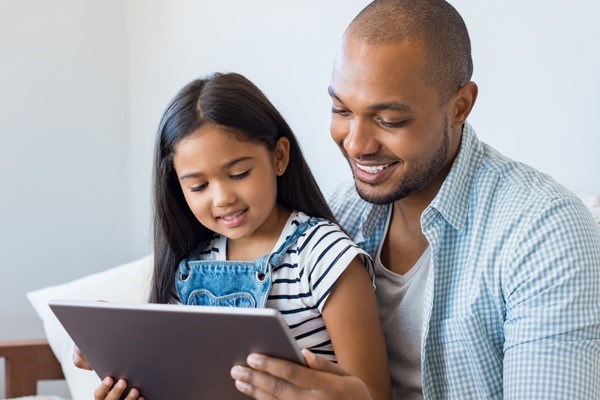 Adult and child use a tablet together.