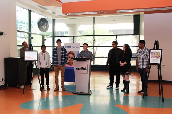 Man speaks at a podium with teens and other staff standing by.