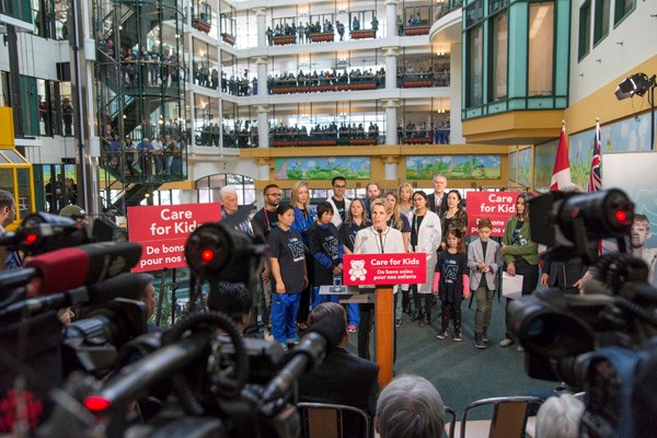 Kathleen Wynne stands on a stage at SickKids in front of reporters
