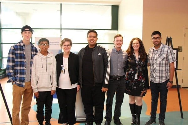 Group of teens and adults poses for a photo, standing side by side in a line.