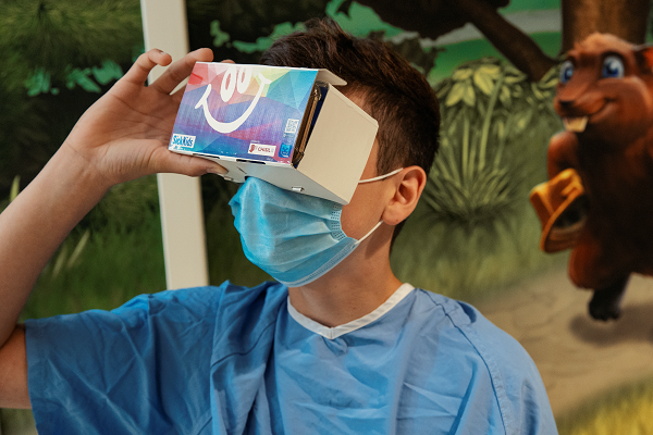 Teen looks into a cardboard VR set.