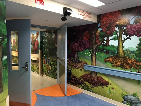 Hospital hallway with open doors showing forest murals.