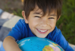 A smiling boy is hugging a big globe