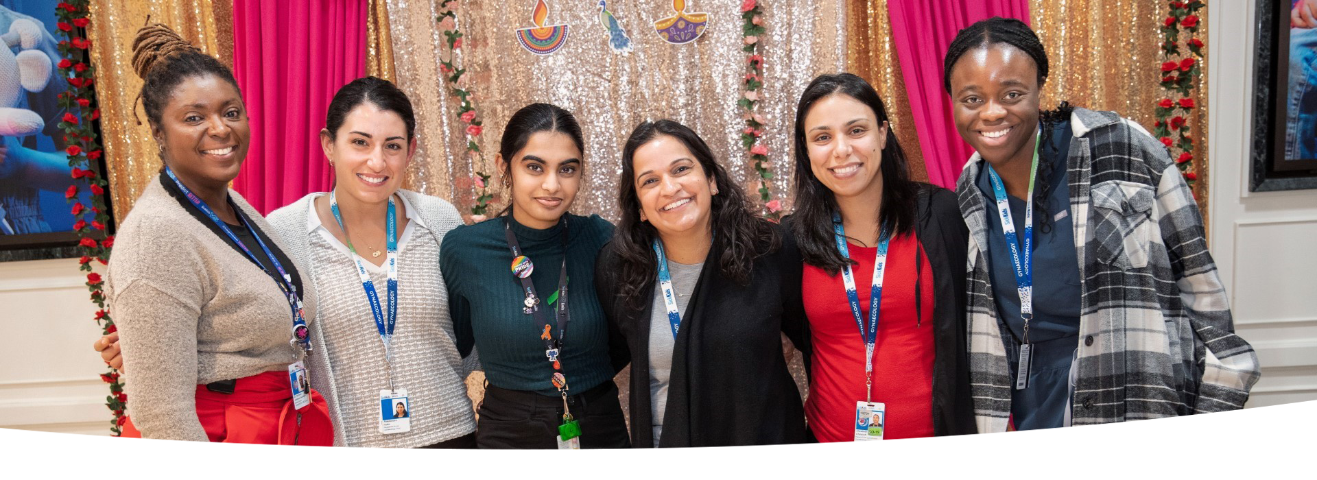 Group of staff stand together in front of a colourful background.