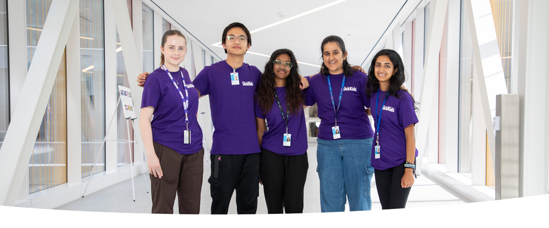 Five youth wearing purple t-shirts stand together smiling.