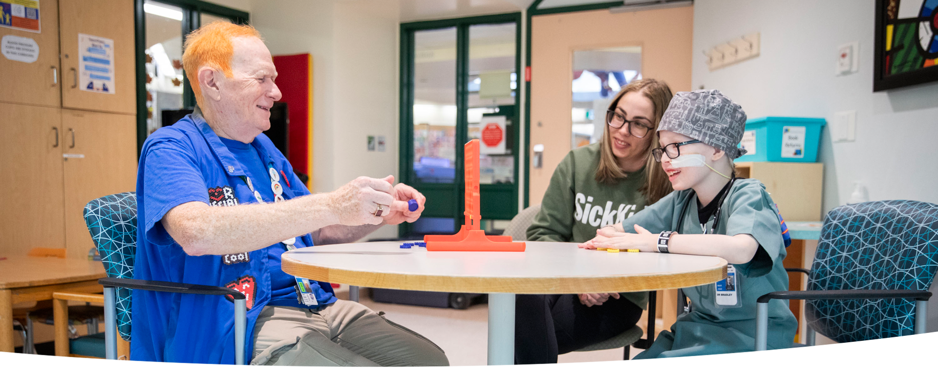 Volunteer plays a board game with a patient and parent.