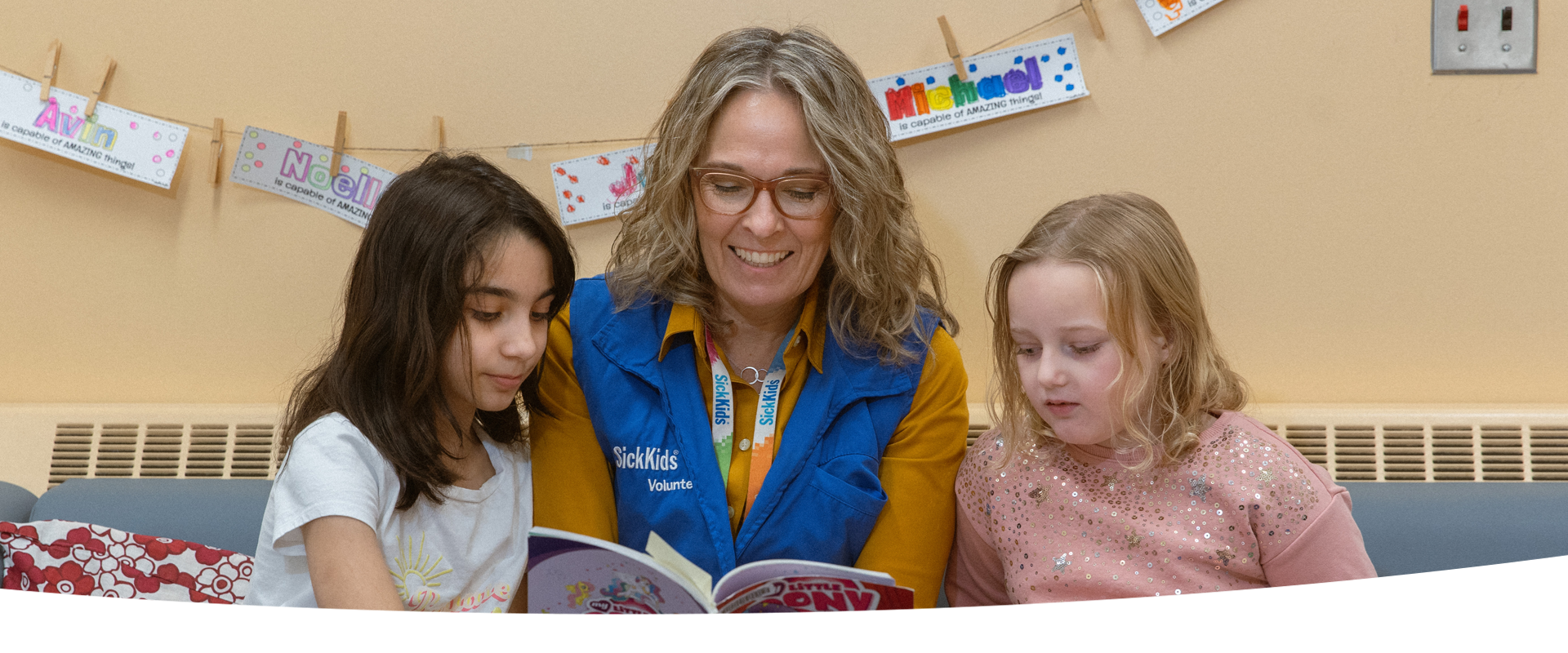 Volunteer reads a book to two children.