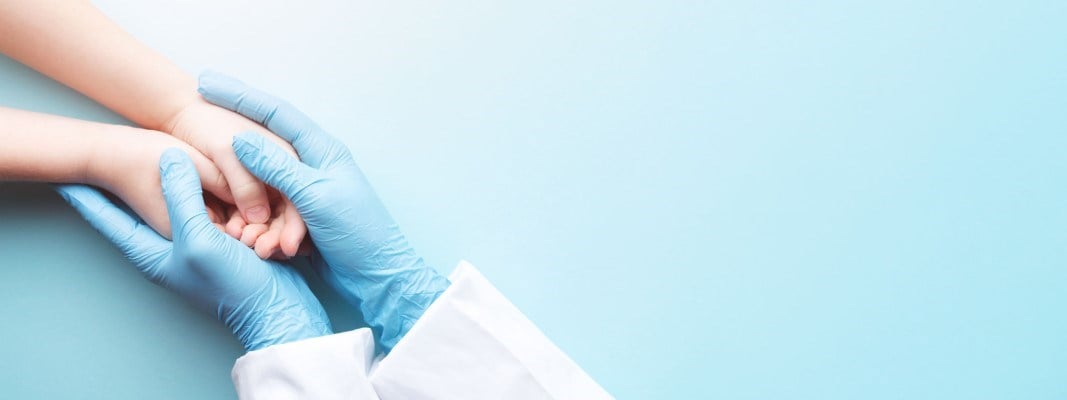 doctor's hands holding young patient's hands