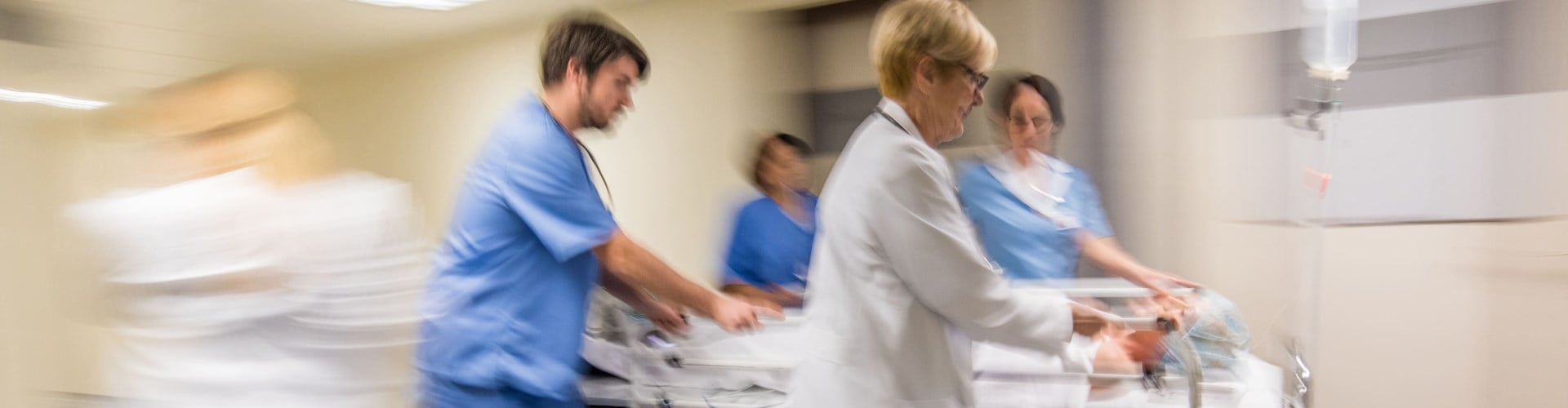 4 staff physicians rushing down the hallway with a stretcher