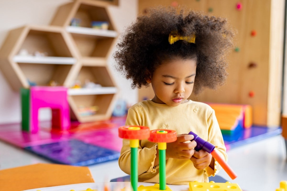 A young child playing with colourful toy blocks.