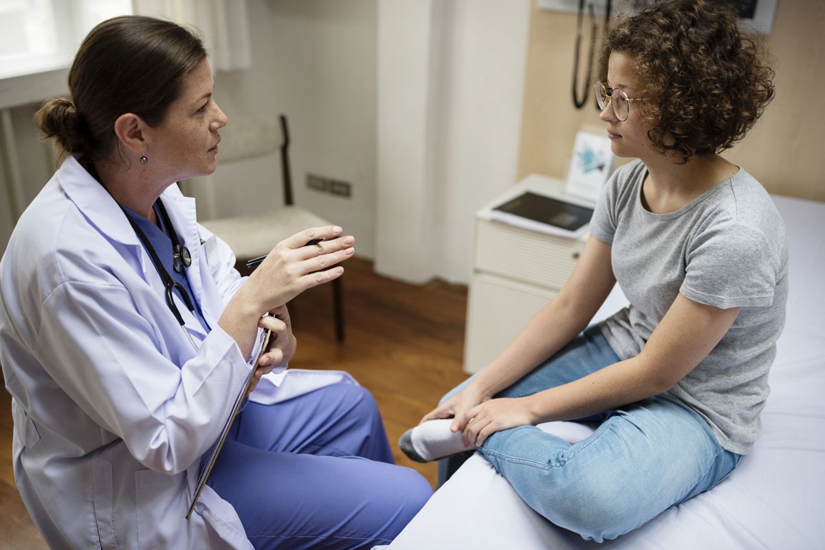 Health care provider and teenager seated together.