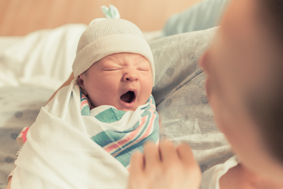 Swaddled baby held by a woman.