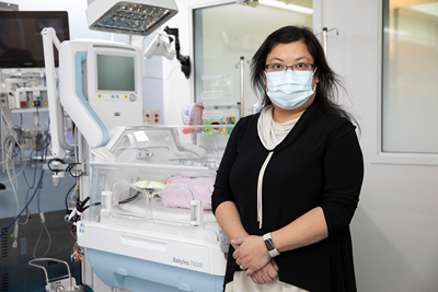 Dr. Emily Tam stands in front of a bed in the neonatal intensive care unit (NICU).