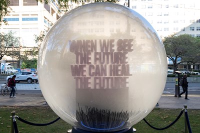 A large crystal ball installation outside of the 555 University Avenue entrance. The text in the ball reads "When we see the future, we can heal the future".