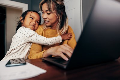 A child hugging a woman who smiles back at the child while on a laptop.