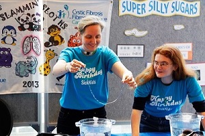 Two staff members dip strands of string into bowls of water