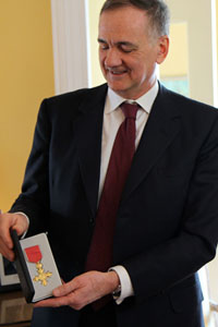 Agostino Pierro holds open a box that contains a golden cross