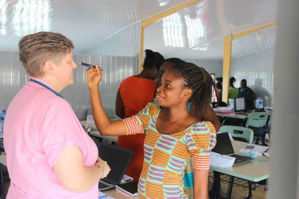 A woman holds a small flashlight up to another woman's eye