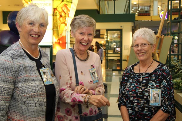 Three women stand side by side wearing name badges.