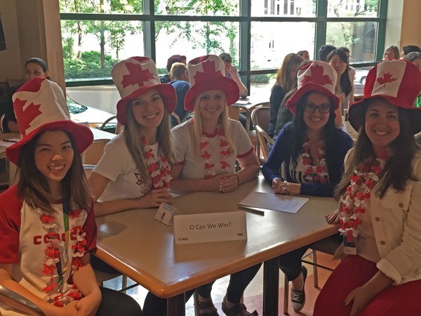 Five women seated together wearing Canada themed hats.