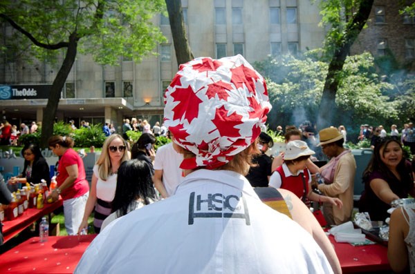 A person stands in front of a crowd wearing a scrub cap printed with red maple leaves.