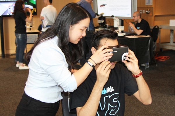 Woman helps someone use a virtual reality set of goggles.