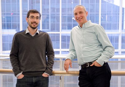 Two men stand leaning against a railing.