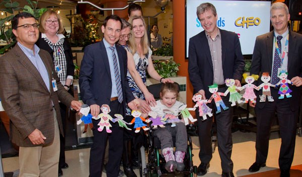 Group of people hold up a children's craft which is a chain of people.