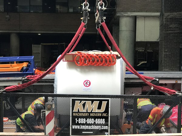 MRI machine sits inside large basket while workers secure it at the base.