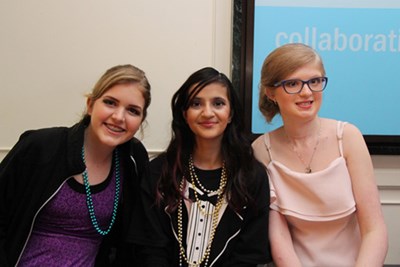 Three girls seated side by side, dressed formally,