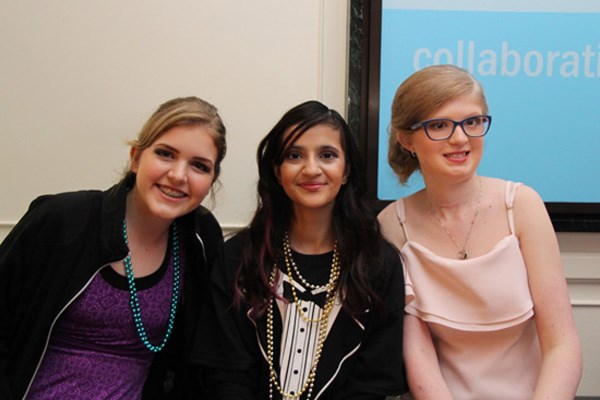 Three girls seated side by side, dressed formally,