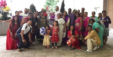 Large group photo of approximately 30 children and adults wearing brightly coloured clothes.