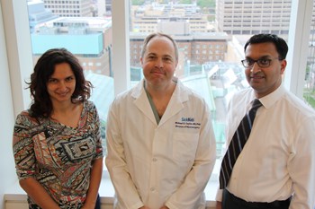 Three staff stand together. One wears a lab coat.