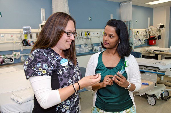 Two women look at their badges.