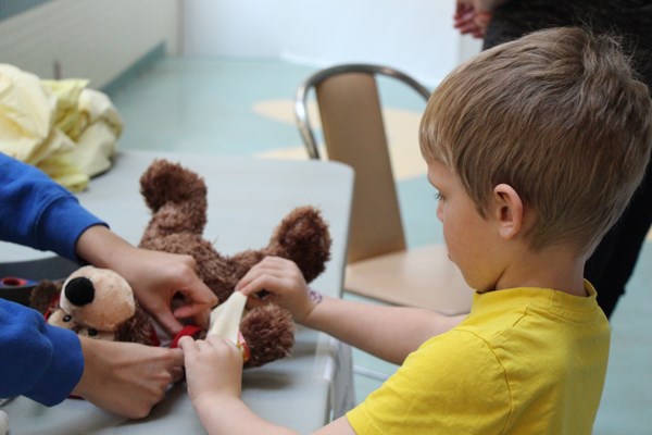 Boy places bandage on a teddy bear.