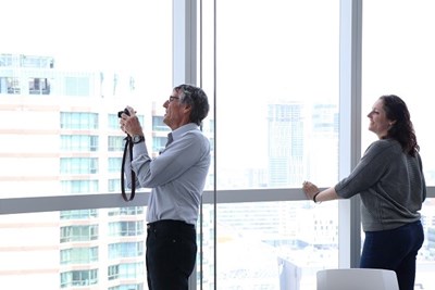 Two people look out the window, one holds a camera.