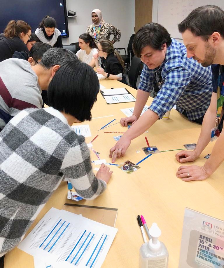 A group of adults leaning in around a table to assemble a puzzle made of straws and pictures