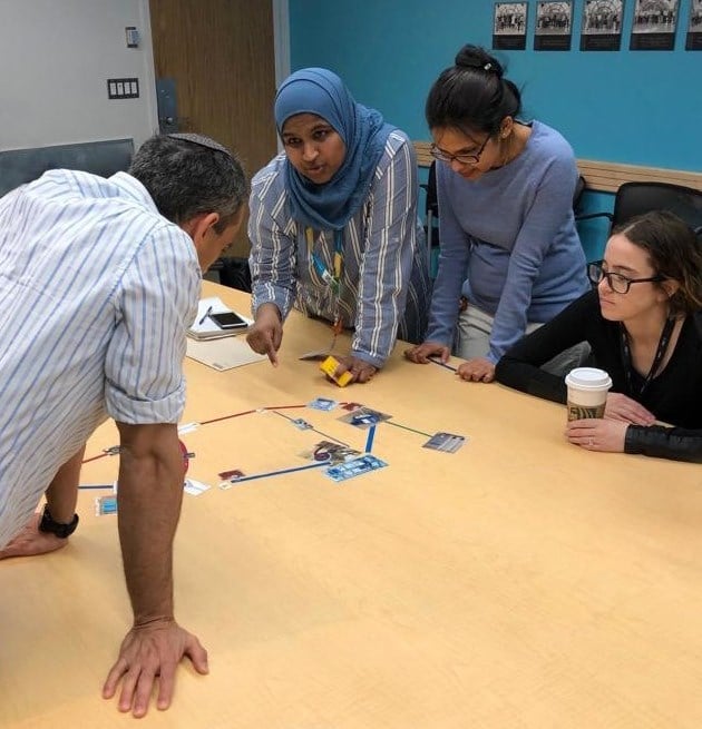 Three staff members observe and listen as Asma speaks to them