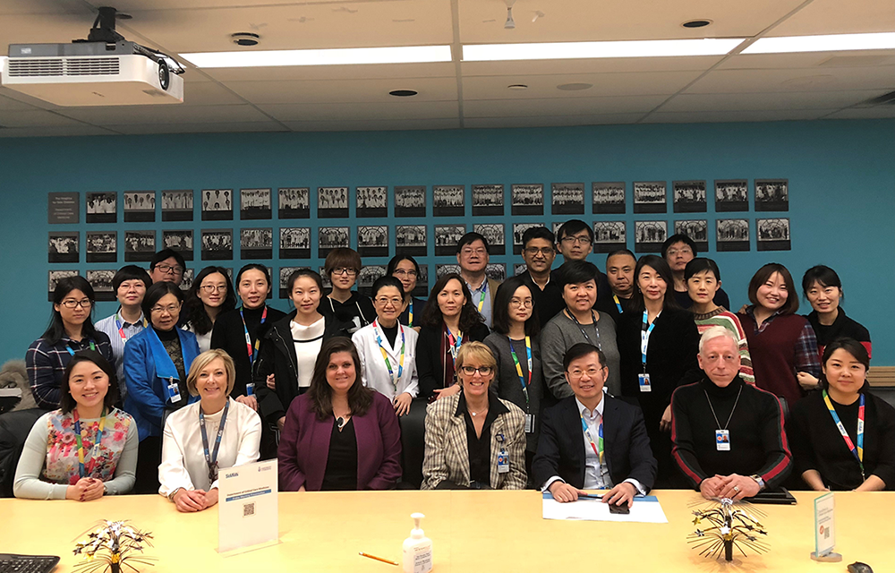 A group of thirty people gathered around a board room table