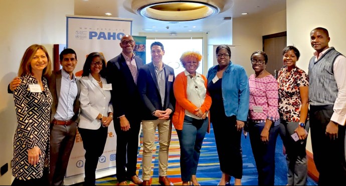 A group of 10 people standing together in front of a banner that reads "PAHO"