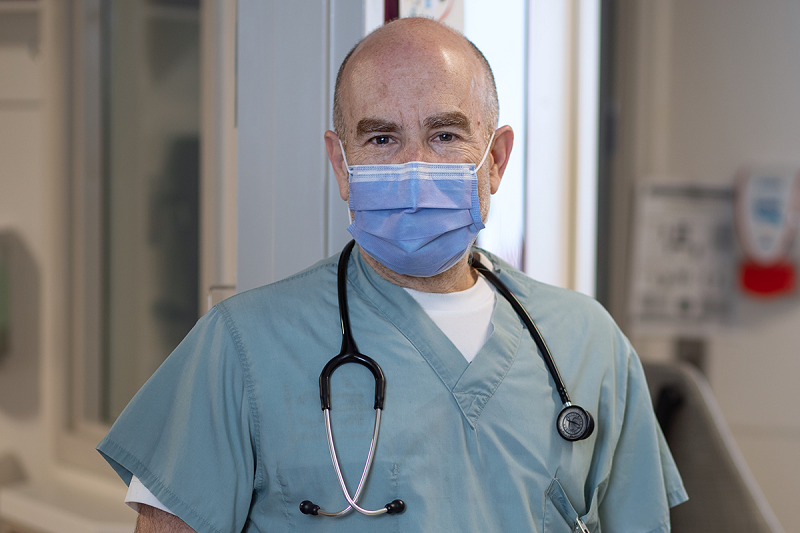 Man wearing a surgical mask, medical scrub top and stethoscope around his neck.