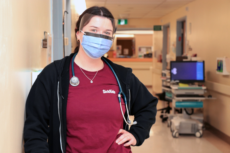 Woman wears a mask, standing in the hallway of the hospital.