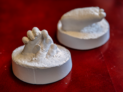 Plaster replicas of a child's hand holding an adult's fingers, and a child's foot.