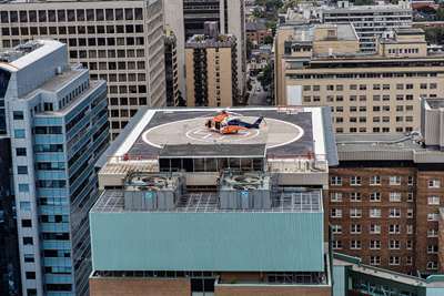 Orange helicopter lands on the roof of a building.