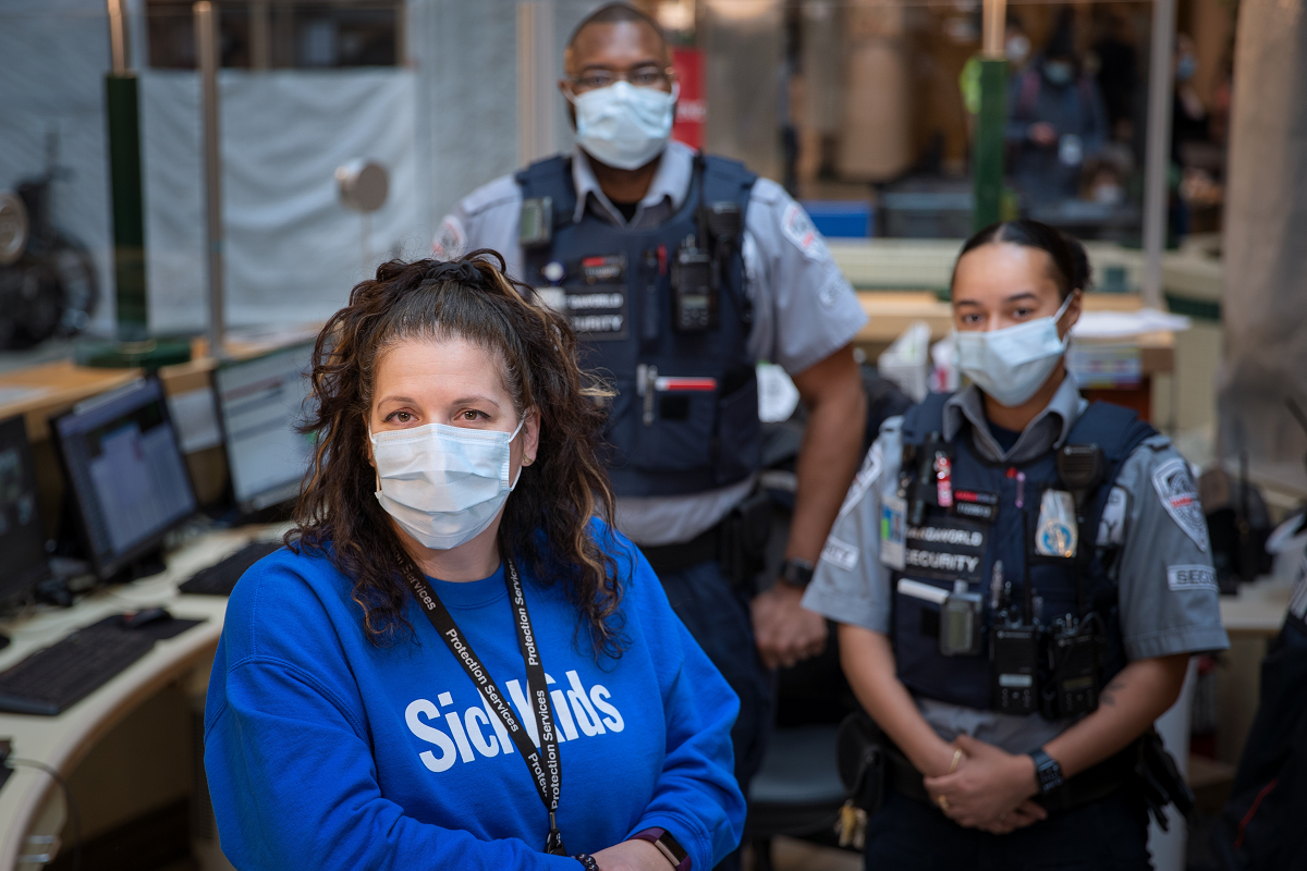 Three people wearing masks. Two are wearing bullet proof vests and other security gear.