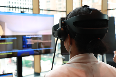 A person wearing a virtual reality headset and looking at a TV screen.
