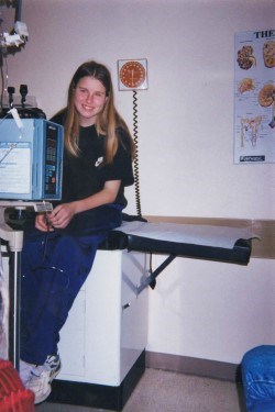 An old photo of Kristina as a child, smiling at the camera as she sits on a medical examination table.
