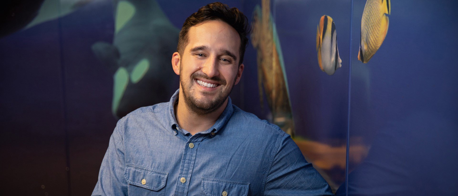 Caleb Tait seated and smiling at the camera.